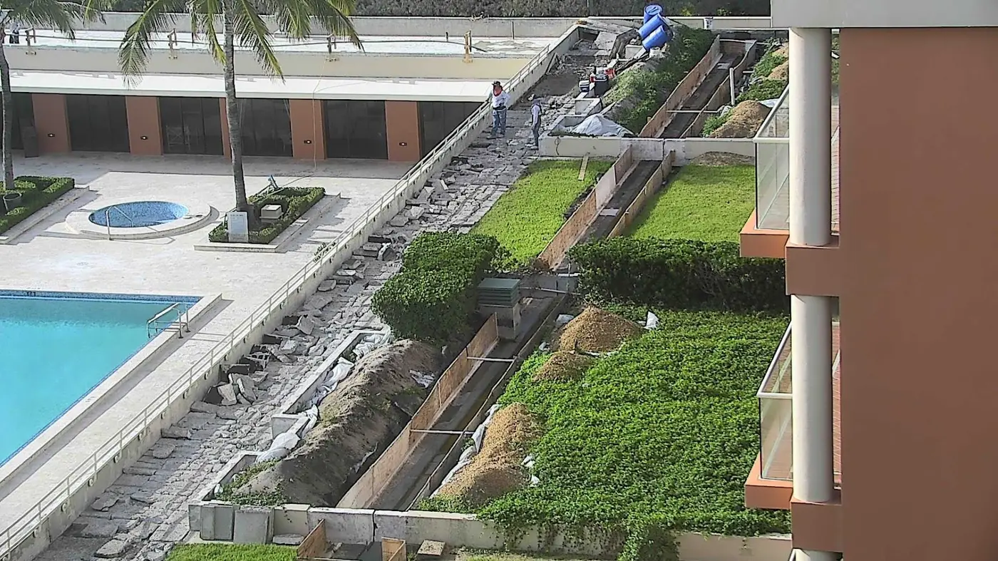 Workers preparing an elevated walkway beside landscaped planters