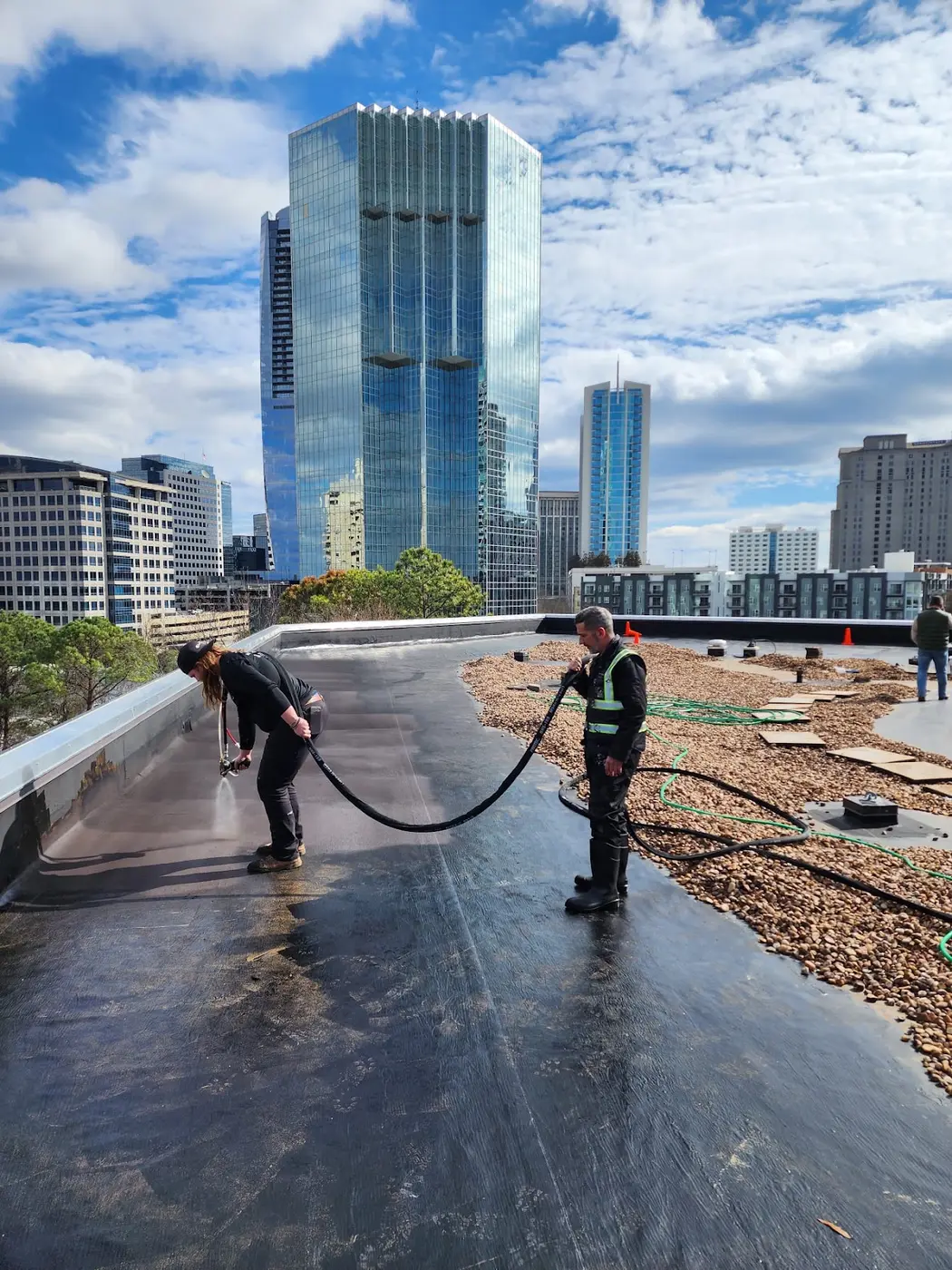 Applicators spraying Wetsuit by Neptune liquid membrane across a high-rise flat roof
